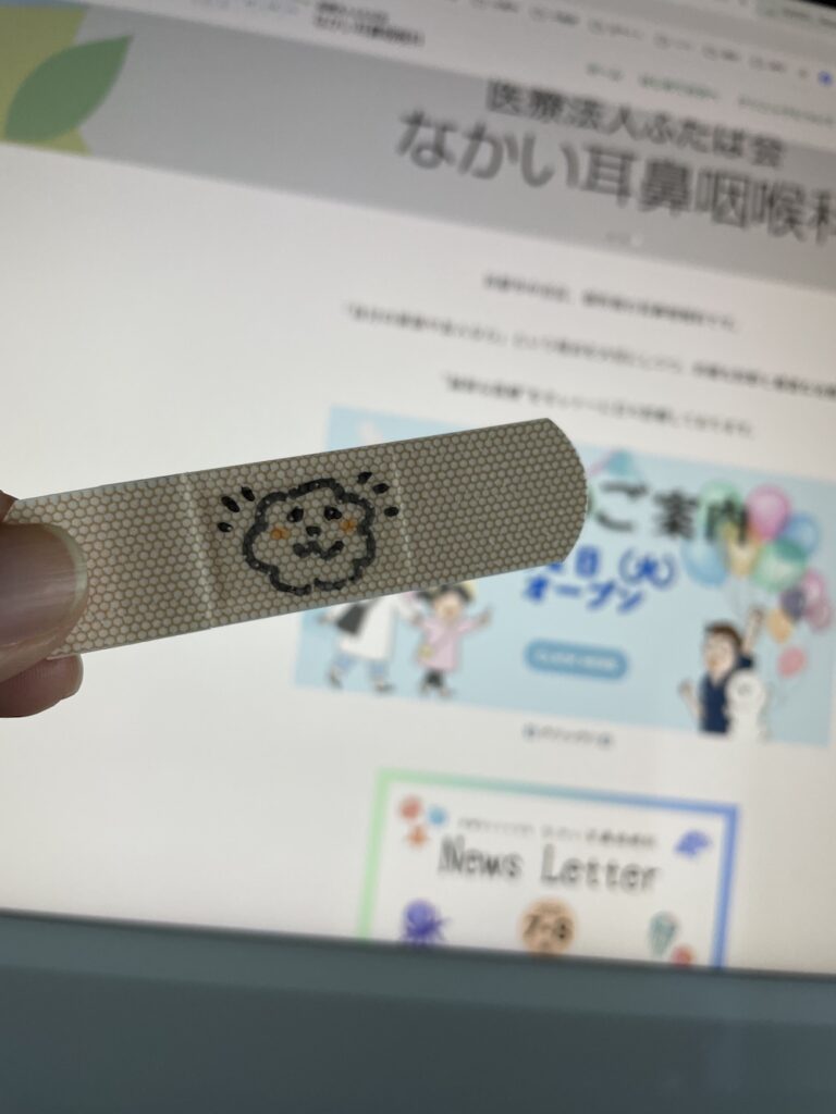 バンドエイドにキャラクターを書いたところの写真。イラスト制作事例|医療法人ふたば会 なかい耳鼻咽喉科 様
